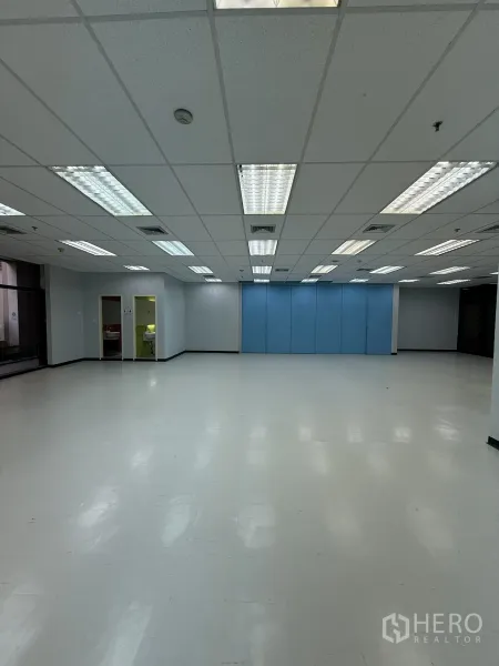 Retail Space for rent in Bang Rak, Bangkok - Wide empty commercial unit with blue partition wall panels, bright lighting and access to back rooms.