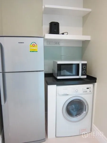 Condominium for rent in Khlong Toei, Bangkok - Utility corner featuring refrigerator, microwave and front-loading washing machine.