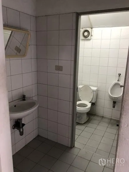 工厂 出租在Pathum Thani - 一层卫生间，瓷砖墙面，设坐便器、小便斗与洗手盆。