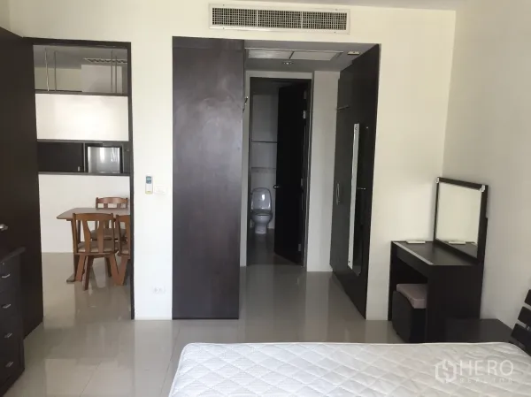 Condominium for rent in Khlong Toei, Bangkok - Bedroom view toward bathroom and dining area with sliding wardrobe doors.