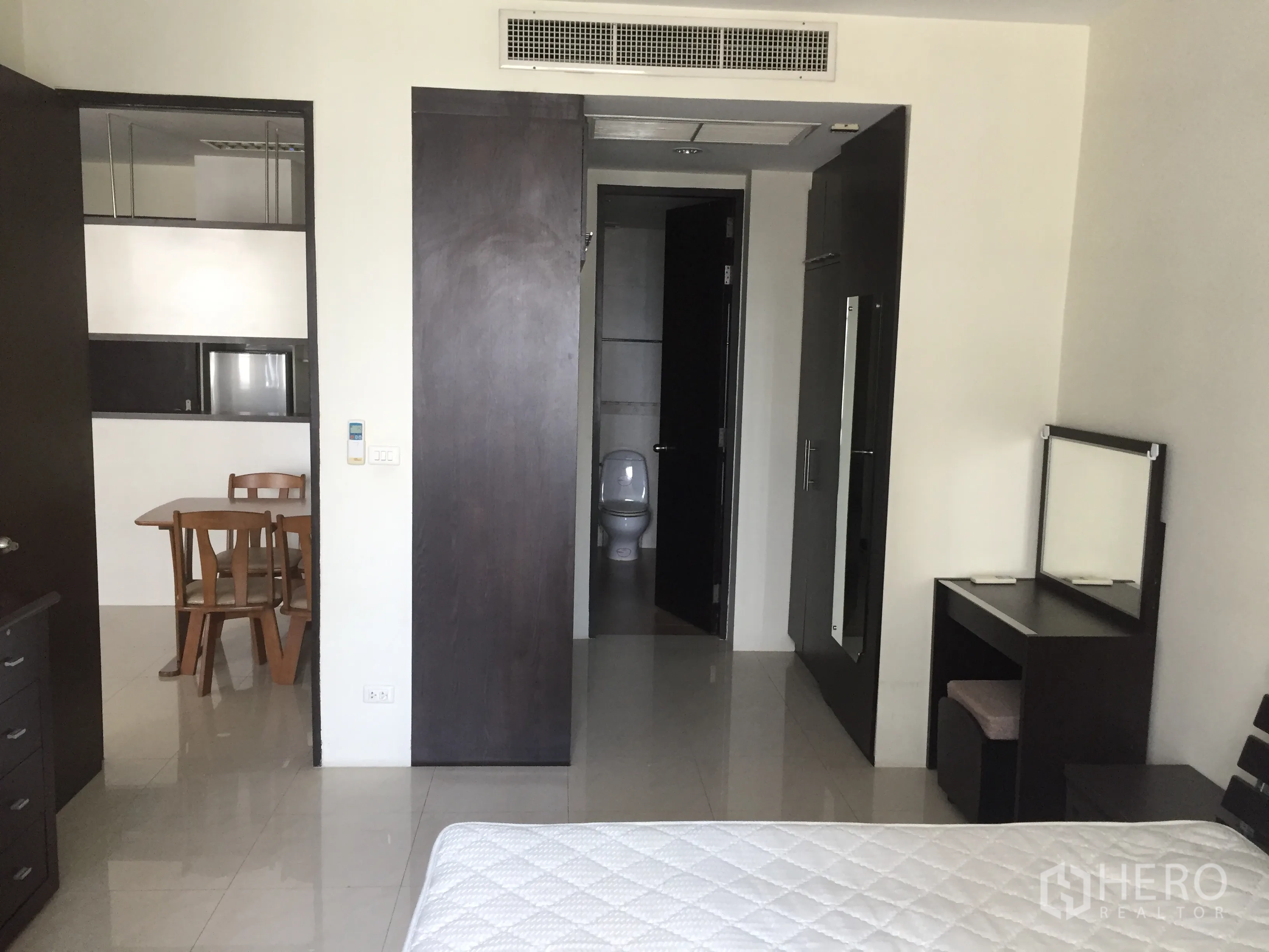 Condominium for rent in Khlong Toei, Bangkok - Bedroom view toward bathroom and dining area with sliding wardrobe doors.