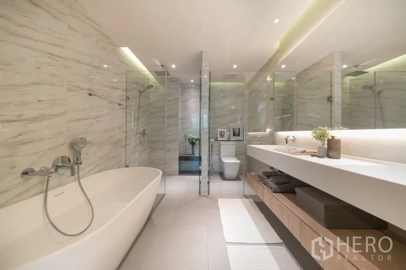 Condominium for rent in Watthana, Bangkok - Spacious bathroom with soaking bathtub, rain shower, and long illuminated vanity.