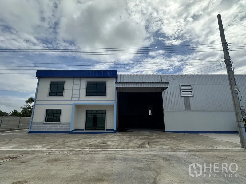 Factory for rent or sale in Sai Noi, Nonthaburi - Front view of factory entrance with high loading bay and large roller door beside the office block.