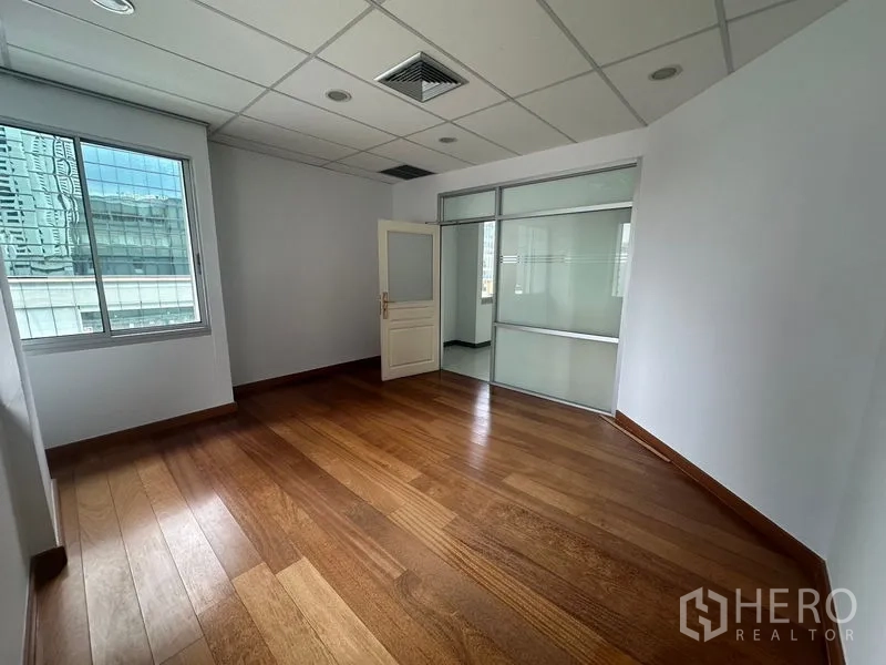 Office Space for rent in Bang Rak, Bangkok - Meeting or executive room with wood floors and a glass partition to the main area.