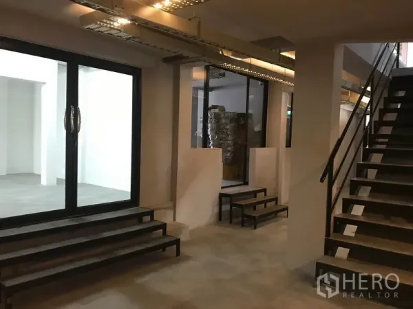 办公空间 出租在Watthana, Bangkok - 大厅区域，金属楼梯、玻璃隔断与多级台阶通向各室。