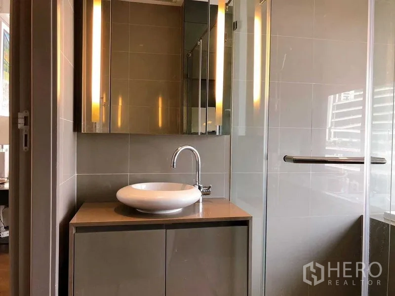 Condominium for rent in Bang Rak, Bangkok - Contemporary bathroom with vessel sink, mirrored cabinets and glass shower.