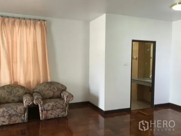 独立式住宅 出租或出售在Huai Khwang, Bangkok - 起居区配花纹沙发、木地板，并有通往瓷砖浴室的门口。