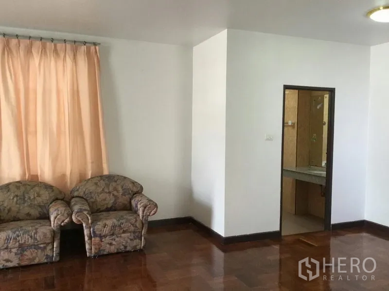 独立式住宅 出租或出售在Huai Khwang, Bangkok - 起居区配花纹沙发、木地板，并有通往瓷砖浴室的门口。