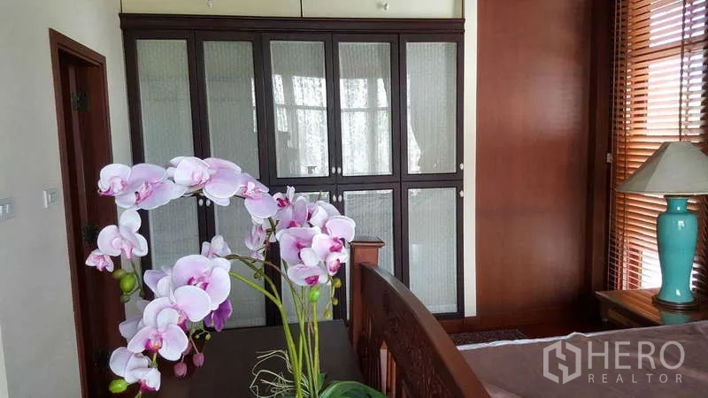 联排别墅 出租在Khlong Toei, Bangkok - 卧室一角，带大型内置衣柜与兰花摆饰