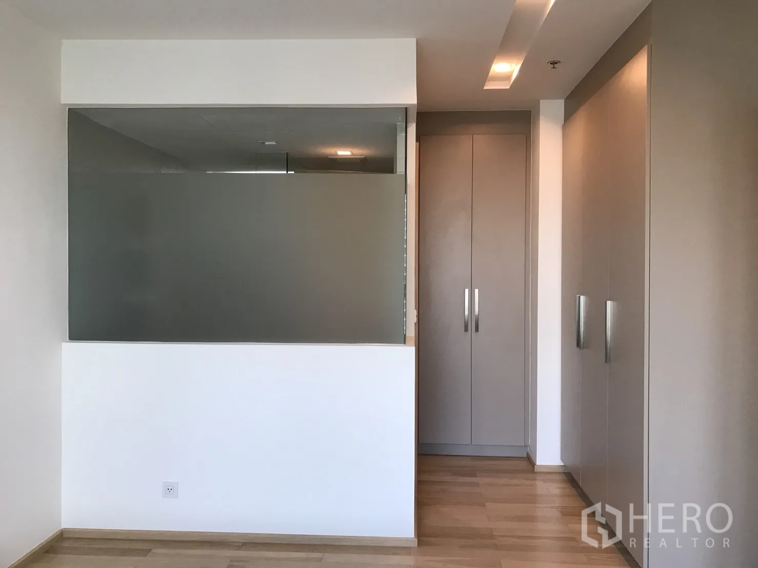 Condominium for rent in Khlong Toei, Bangkok - Hallway with built‑in wardrobes and a frosted glass partition in a modern condominium.