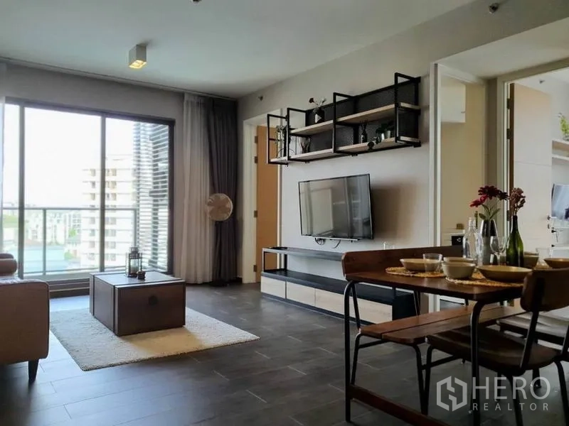 公寓 出租或出售在Watthana, Bangkok - 明亮客厅带落地窗与阳台景观，墙面挂装电视。