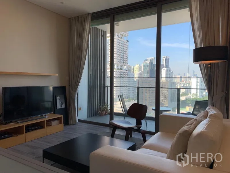 คอนโด ให้เช่าในWatthana, Bangkok - ห้องนั่งเล่นสว่างพร้อมโซฟา ชั้นวางทีวี และประตูกระจกเต็มบานเปิดสู่ระเบียงชมวิวสกายไลน์ เขตวัฒนา กรุงเทพฯ