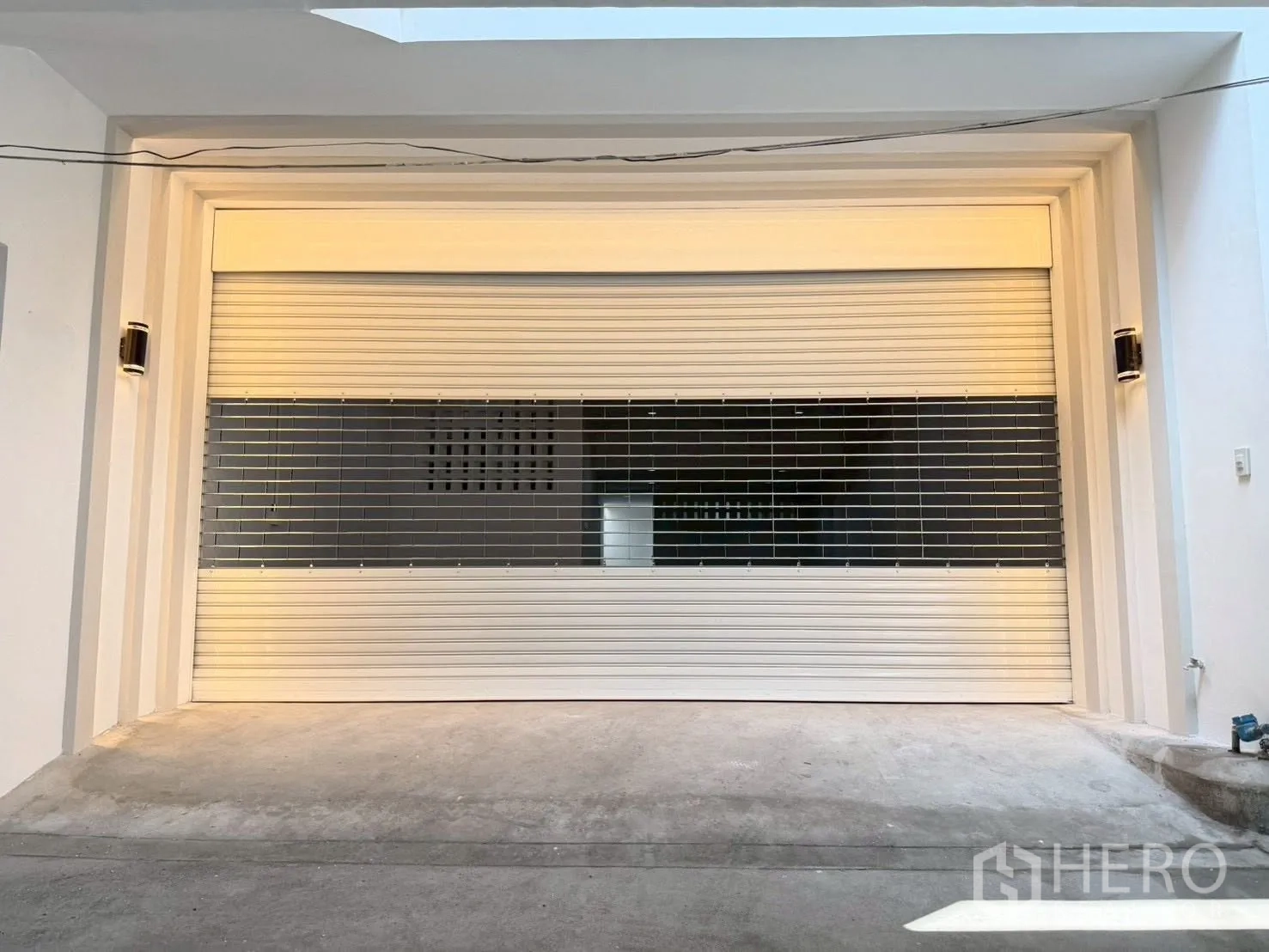 Townhouse for sale in Phra Khanong, Bangkok - Secure roller shutter garage entrance with exterior lighting.