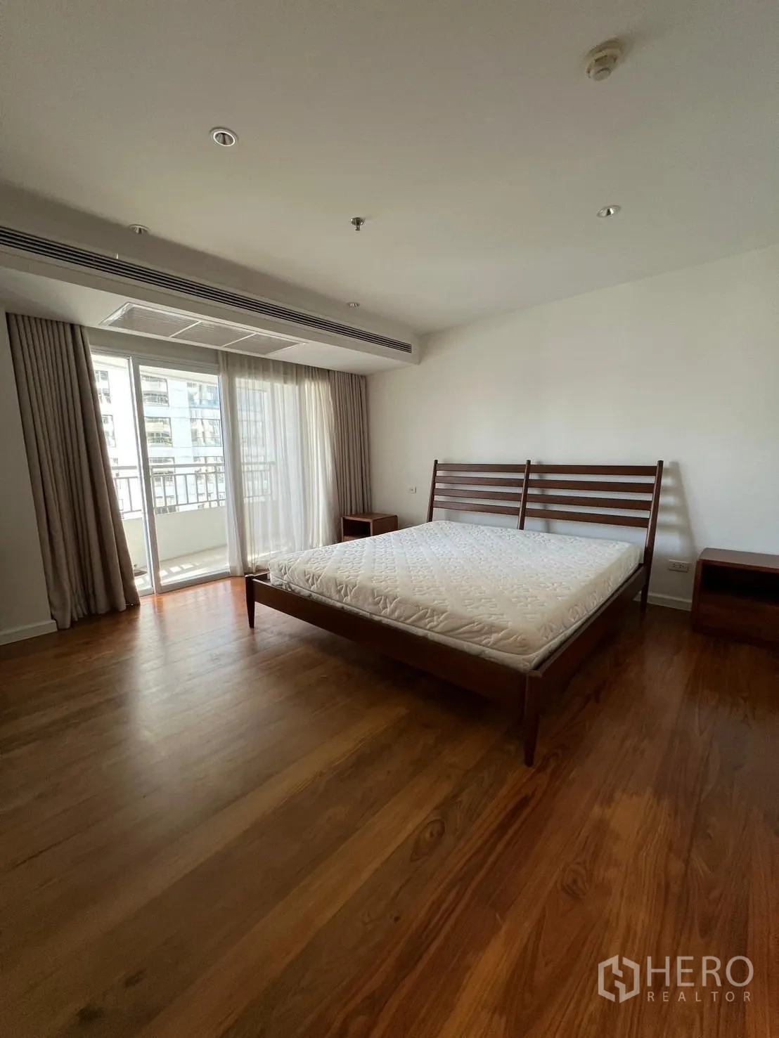 Condominium for rent or sale in Sathon, Bangkok - Bright bedroom with wooden floors, bed frame and sliding doors to a balcony.