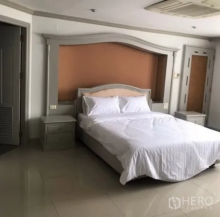 公寓 出租在Watthana, Bangkok - 主卧另一角度，双人床、装饰床头与床头柜，通向套内卫浴的门。