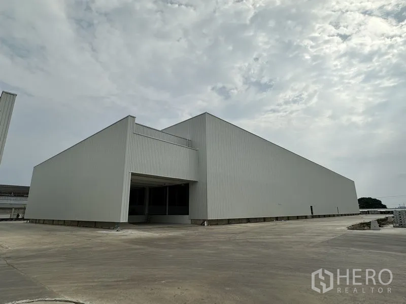 工厂 出租在Pathum Thani - 大型高跨厂房的斜角外观，配备宽敞卡车回转 yard。