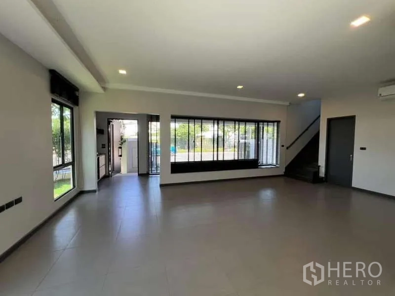 独立式住宅 出租或出售在Bang Phli, Samut Prakan - 一层大面积起居空间，超宽窗面与通往二层的楼梯。