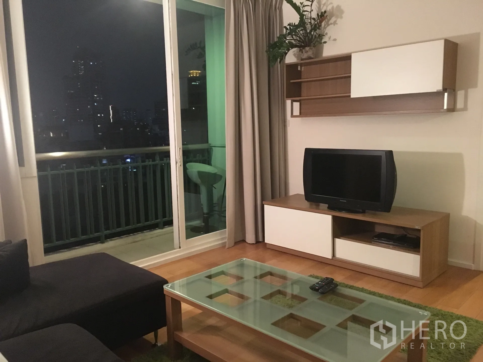 公寓 出租在Watthana, Bangkok - 客厅设沙发与电视柜，推拉玻璃门通向阳台