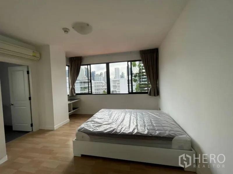 Condominium for rent in Watthana, Bangkok - Bedroom with double bed, wraparound windows and urban outlook.