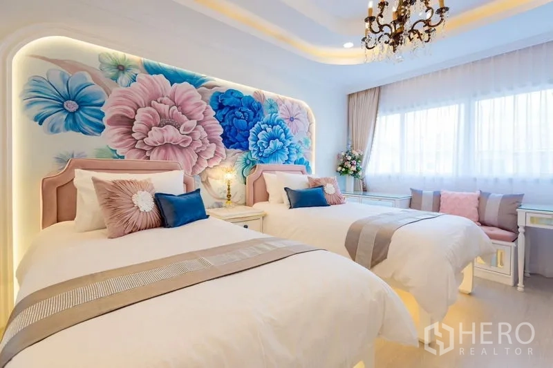 Townhouse for rent in Lat Phrao, Bangkok - Twin bedroom highlighted by a large floral feature wall, chandeliers and wide windows with seating.