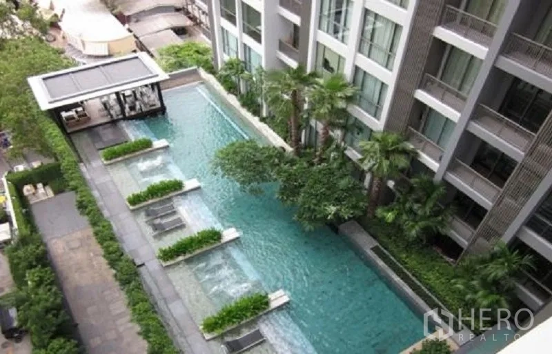 คอนโด ให้เช่าในWatthana, Bangkok - ภาพมุมสูงสระว่ายน้ำสไตล์รีสอร์ทของคอนโด มีเตียงนอนเล่นในน้ำและสวนเขียวขจี