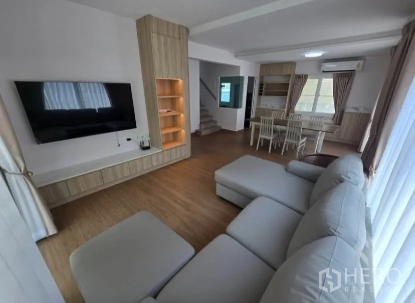 独立式住宅 for rent in Bang Phli, Samut Prakan - 客厅配转角沙发、大屏电视，旁连餐区。