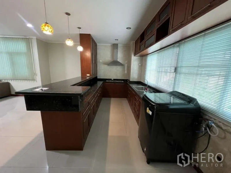 带办公室的家 出租或出售在Min Buri, Bangkok - U型厨房，黑色台面、抽油烟机与大面积窗户采光。