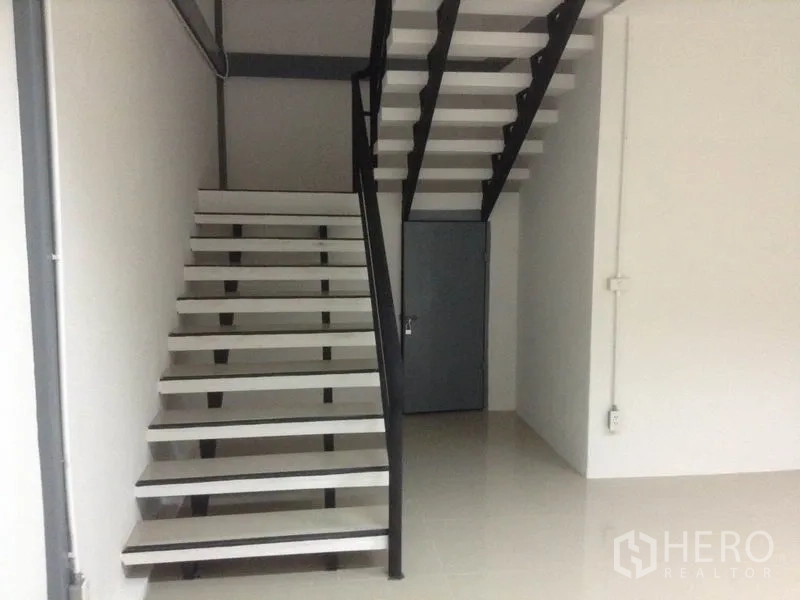 Warehouse for rent in Bang Kapi, Bangkok - Close-up of metal staircase leading to an upper level with an under-stair storage door.