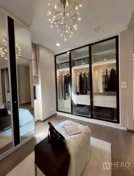 独立式住宅 出租在Lat Phrao, Bangkok - 步入式衣帽间，玻璃推拉衣柜、枝形吊灯与软包坐凳。