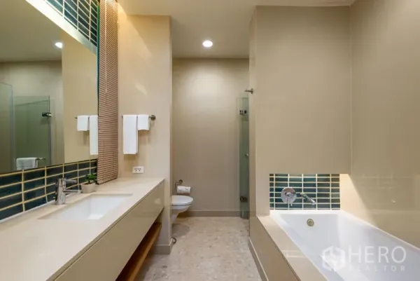 Condominium for rent in Bang Kho Laem, Bangkok - Modern bathroom with long vanity, bathtub, separate glass shower and neutral tiles.