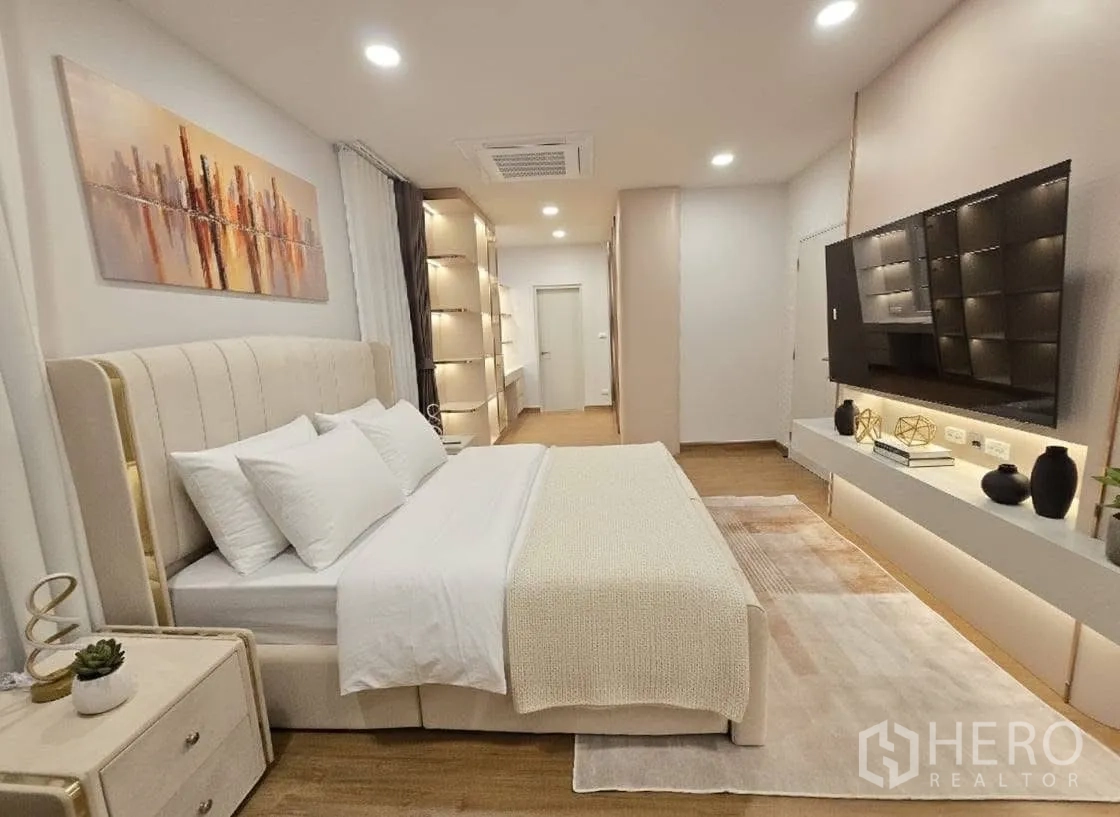 Detached House for rent or sale in Bang Phli, Samut Prakan - Master suite view showing bed, ceiling cassette AC, long TV wall and display shelves.