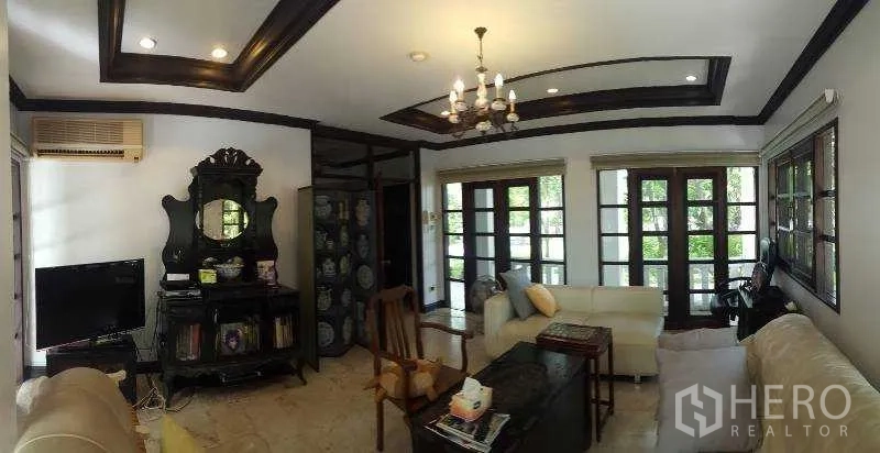 独立式住宅 出租在Bang Phli, Samut Prakan - 采光充足的客厅，格栅天花、吊灯与沙发区。