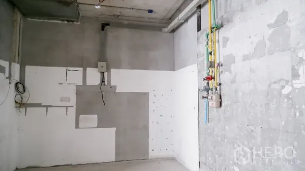 Retail Space for rent in Watthana, Bangkok - Service wall with utility conduits and wiring in a bare retail interior with cement finish.