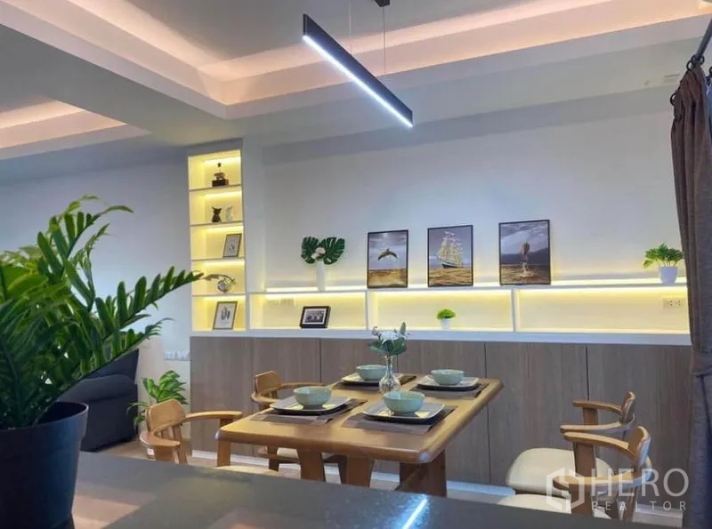 Townhouse for rent in Prawet, Bangkok - Dining space view with modern linear pendant and decorative display shelves.