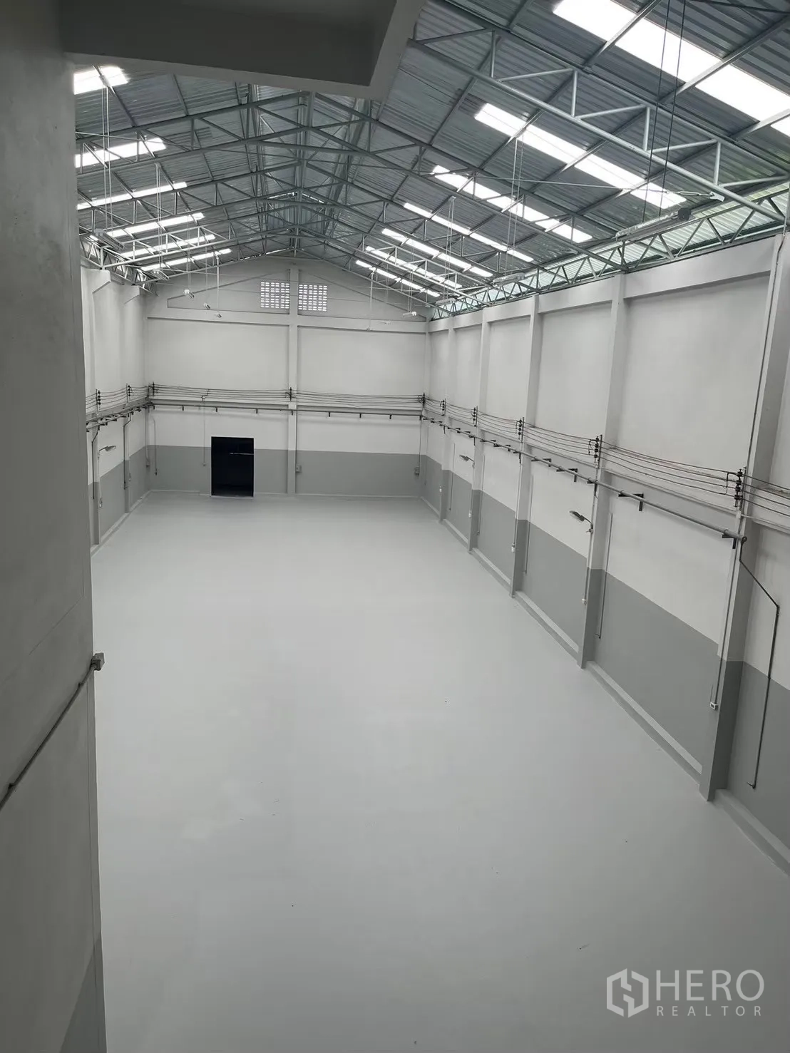 Factory for rent in Bang Bua Thong, Nonthaburi - High-roof warehouse with steel truss structure and skylight panels.