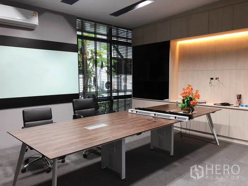 Office Space for rent in Bang Na, Bangkok - Team workspace with twin wood desks, built‑in cabinetry, whiteboard and window blinds.