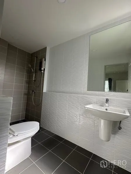 Detached House for sale in Nonthaburi - Guest bathroom with gray tiles, shower zone and white sanitary ware.