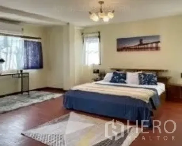 Detached House for rent in Phra Khanong, Bangkok - Spacious bedroom with wood floors, windows, double bed and a small study nook.