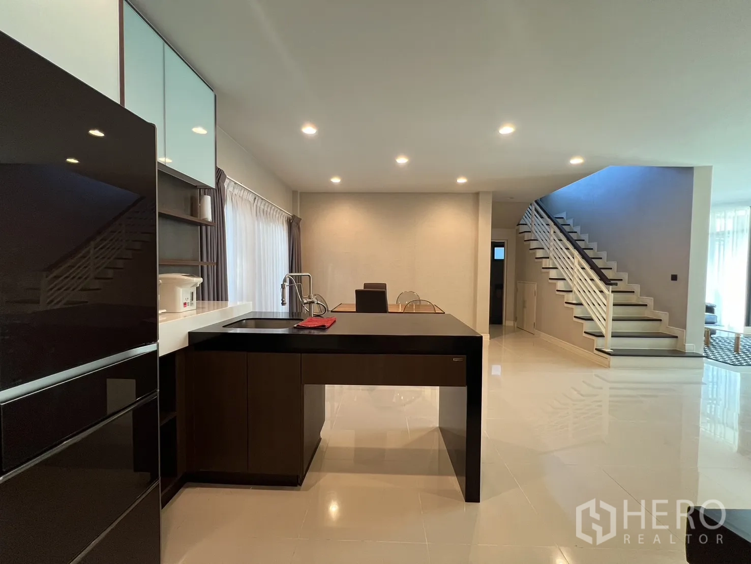 独立式住宅 出租或出售在Bang Kapi, Bangkok - 茶点岛台与开放楼梯，宽敞明亮的一层空间。
