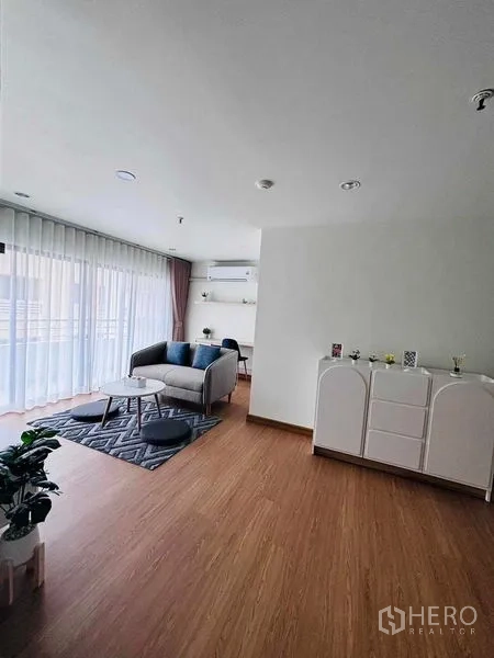 Shophouse for rent in Watthana, Bangkok - Spacious living room with cabinet, wood flooring and access to a bright balcony.
