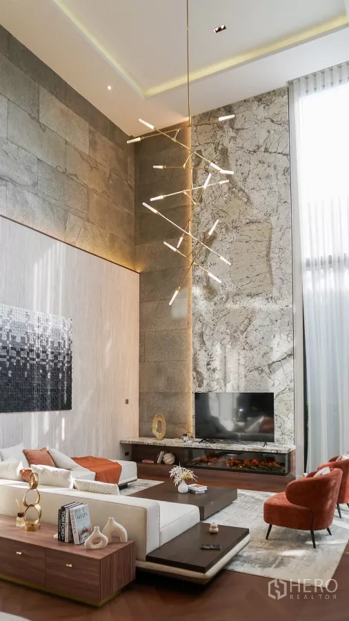Detached House for rent or sale in Bang Kapi, Bangkok - Double-height living room with marble feature wall, designer chandelier and TV over a long hearth.