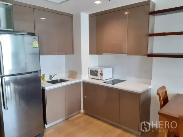 公寓 出租在Khlong Toei, Bangkok - 现代转角厨房，亮面橱柜、不锈钢冰箱、电磁炉与微波炉。