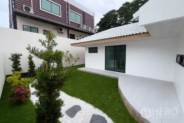 บ้าน ขายในPrawet, Bangkok - สวนจัดแต่งด้วยสนามหญ้า ทางเดินหินสีขาว พุ่มไม้ และประตูกระจกบานเลื่อน