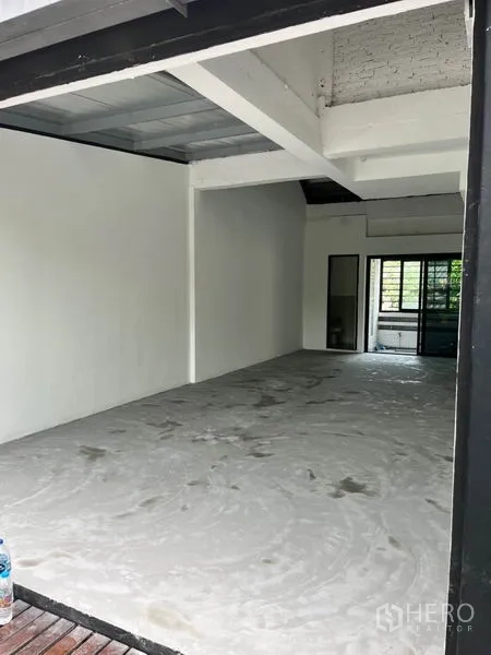 零售空间 出租在Watthana, Bangkok - 从入口望向开放式店面，纵深布局，外露梁结构与推拉玻璃门通向绿意露台。