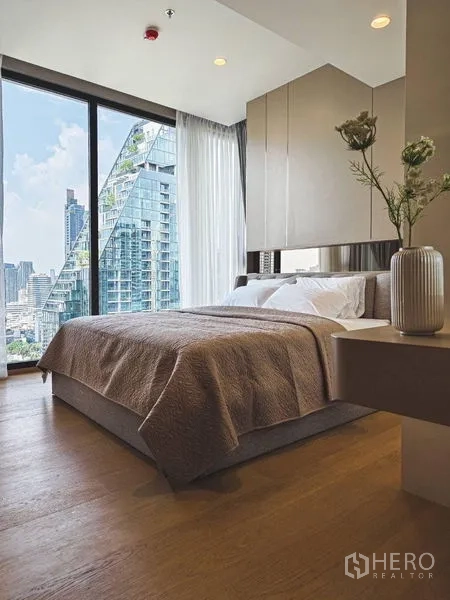 公寓 出租在Bang Rak, Bangkok - 采光充足的卧室，木地板与简洁台面花瓶，享城市景观。
