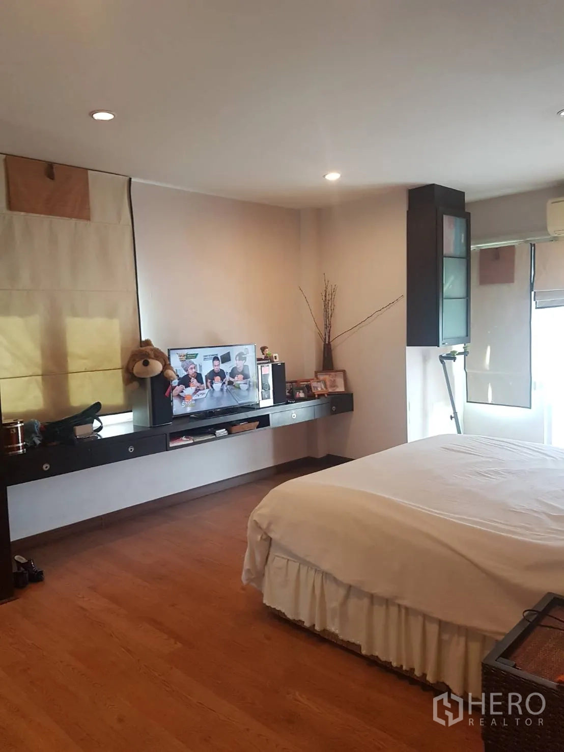 Detached House for sale in Lat Krabang, Bangkok - Spacious master bedroom with wood flooring, double bed, wall-mounted desk and TV.