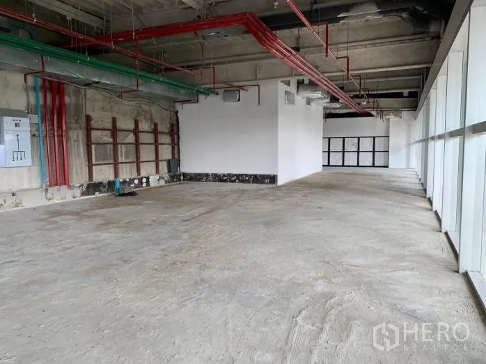 零售空间 出租 - 长条形毛坯商铺，红绿管线、电箱与整排玻璃立面。