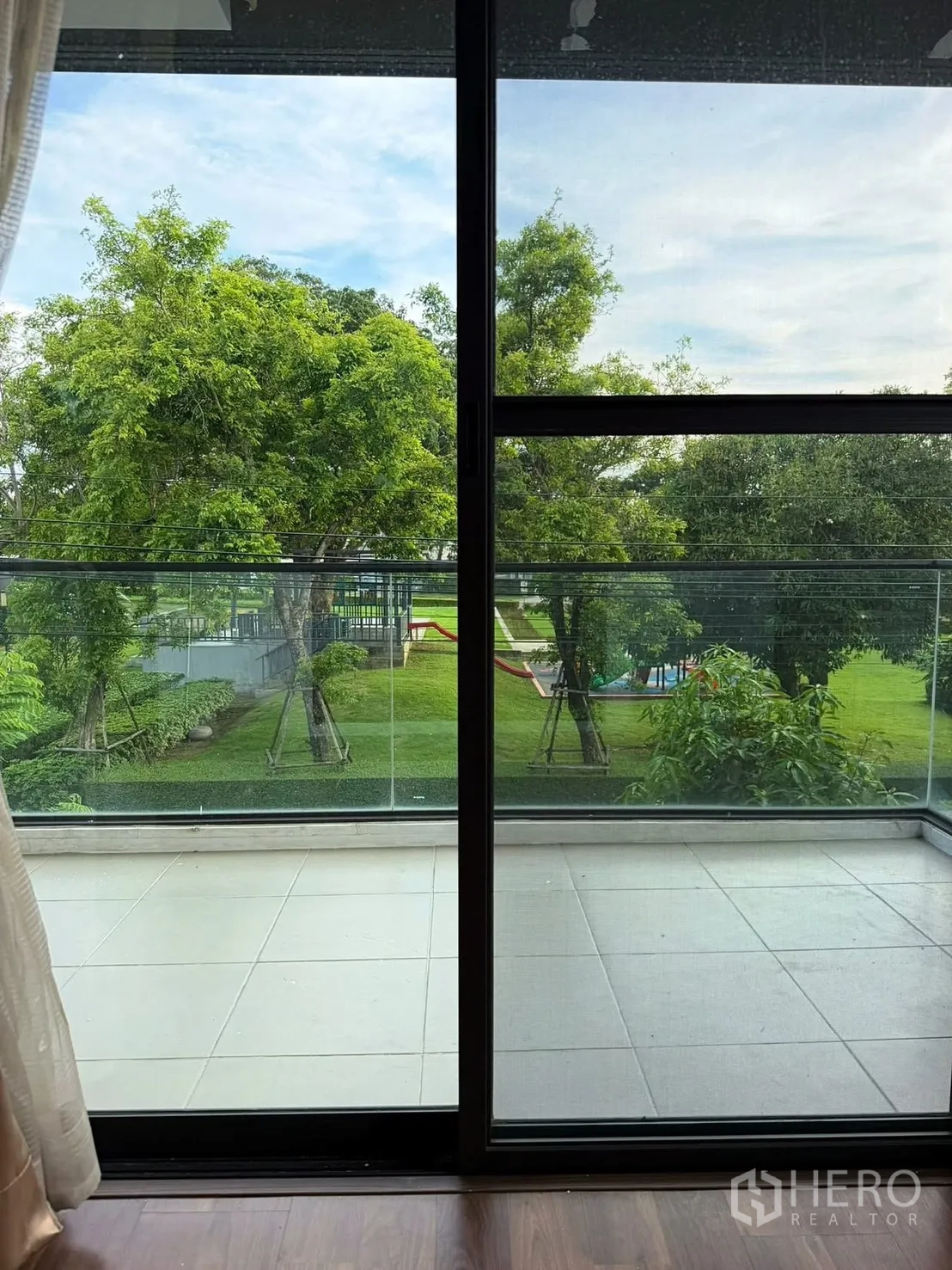 Detached House for rent in Prawet, Bangkok - Balcony with glass railing overlooking green trees and a landscaped park area.