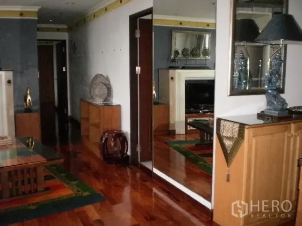Condominium for rent in Pathum Wan, Bangkok - Hallway with polished wooden floors, a large wall mirror, built-in cabinets and modern decor.