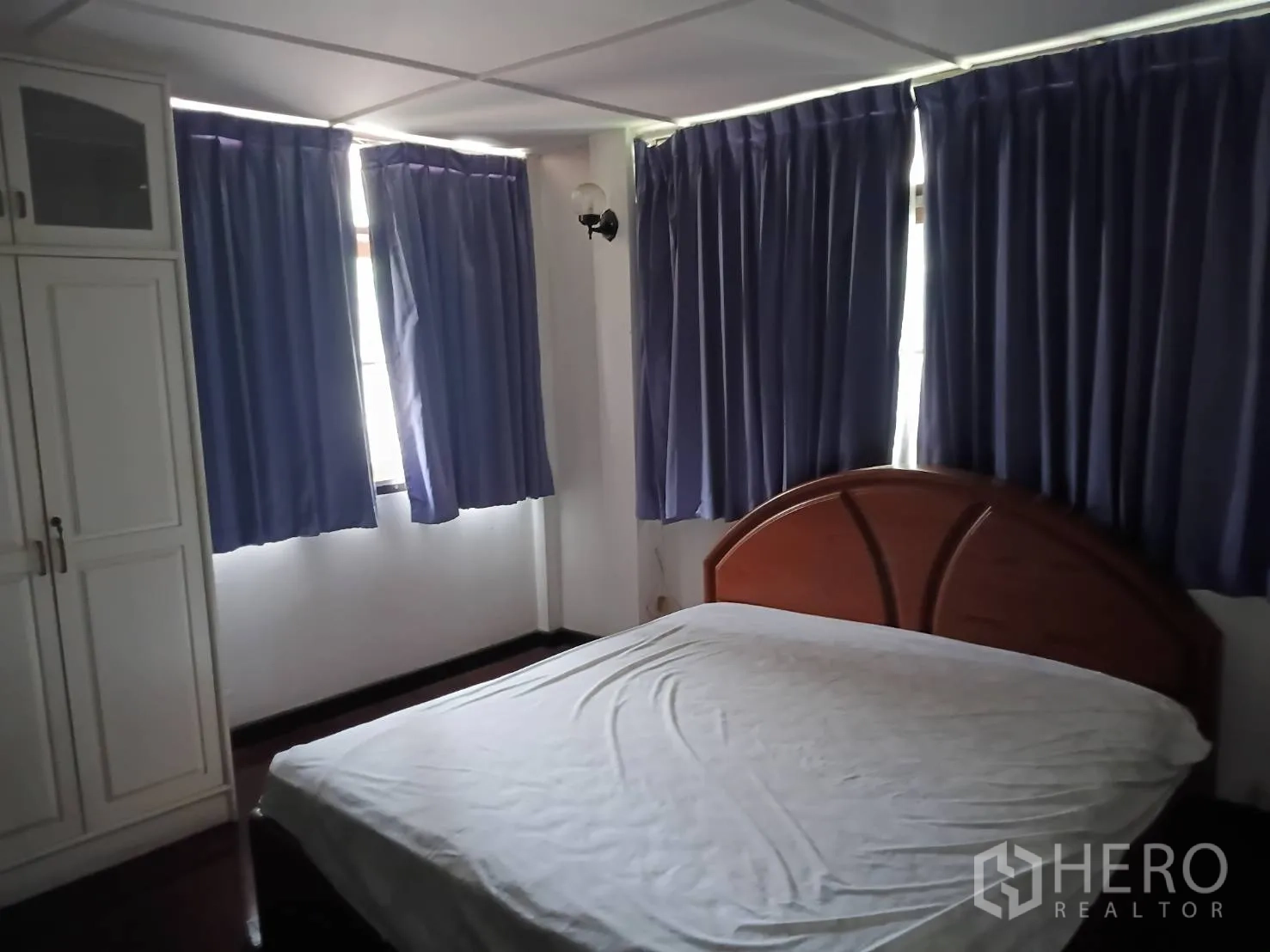 独栋房屋 for sale in Watthana, Bangkok - 卧室配床、衣柜及多扇带深色窗帘的窗户。